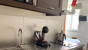 A compact kitchen with a microwave, a coffee maker, a sink, and a dishwasher. - Camaret Guesthouse LE Vauban (NEUF BRISACH)