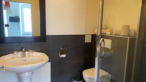 A modern bathroom with a pedestal sink, a toilet, and a glass shower enclosure. - Camaret Guesthouse LE Vauban (NEUF BRISACH)