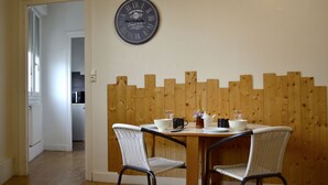 Un coin repas agrémenté d’un lambris en bois, d’une horloge murale et de deux chaises en osier.