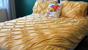 Ein Bett mit einer gelben Steude und einem Kissen mit Blumenmuster.