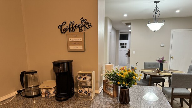 Eine Küchenarbeitsplatte mit Kaffeemaschine, Kaffee-Pods-Spender und einer Vase mit Blumen.