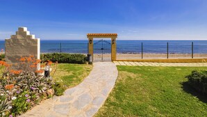 Un sendero de piedra que lleva a un portón de acceso a la playa, con vista despejada del océano.