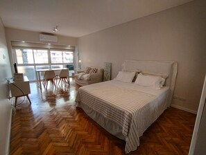 A bedroom with a large bed, a desk, and a chair. - Estudio en Recoleta (Buenos Aires)