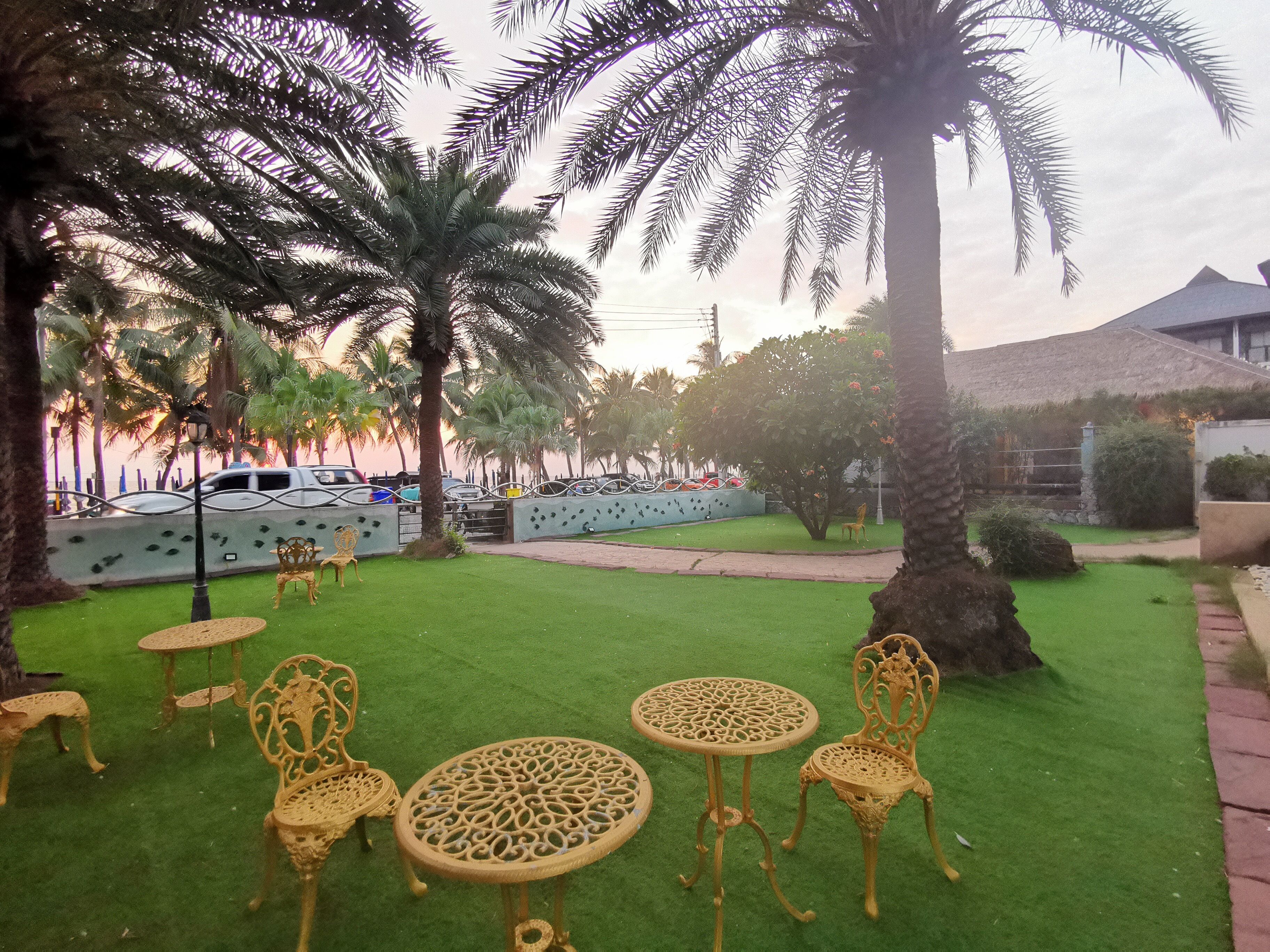 A garden with artificial grass, palm trees, and outdoor furniture.