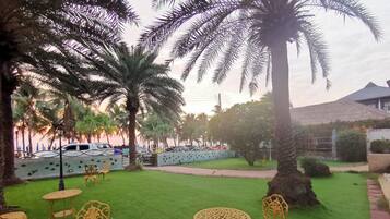 A garden with artificial grass, palm trees, and outdoor furniture.