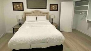 Ein Schlafzimmer mit einem Bett, zwei Nachttischen, einem Kleiderschrank und einer Deckenleuchte.