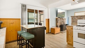 Une cuisine dotée d’un îlot central, de meubles en bois, d’une cheminée en pierre et d’une grande fenêtre.