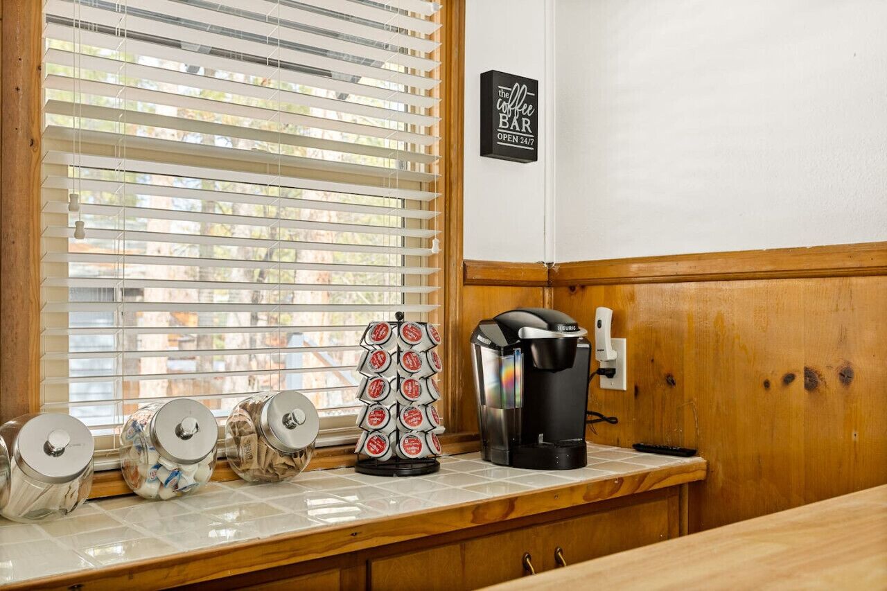 Una encimera de cocina con una cafetera, tarros de café y un letrero para una cafetería.