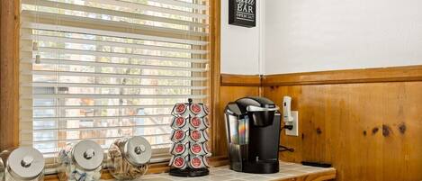 Una encimera de cocina con una cafetera, tarros de café y un letrero para una cafetería.