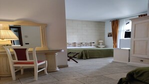 Une chambre comprenant un lit, un bureau avec une chaise, un miroir et une armoire.