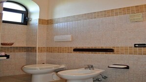 Une salle de bain avec deux toilettes, un lavabo et une fenêtre.