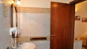 Une salle de bain équipée d’un lavabo, d’un miroir et d’un sèche-cheveux.