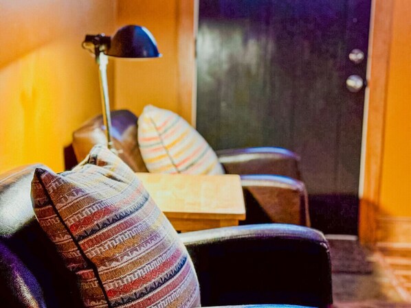 Un coin salon confortable avec un canapé et un fauteuil, une lampe et un coussin à rayures.