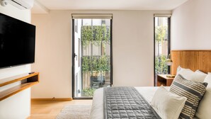 Een slaapkamer met een bed, een televisie, een schuifdeur naar een balkon en een nachtkastje met een lamp.