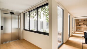 Een modern interieur met een lift, grote ramen, houten vloeren en een keukenhoek.