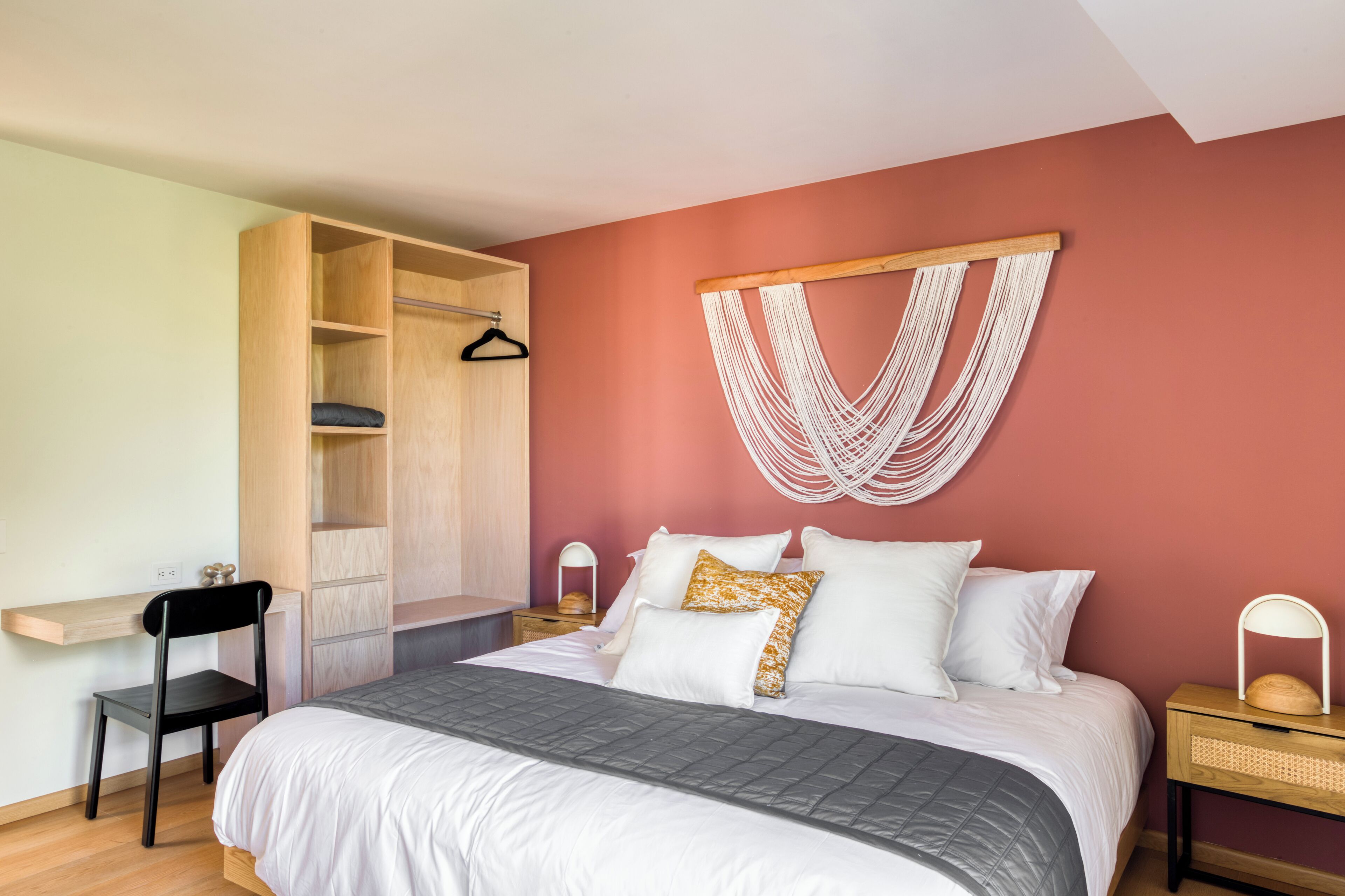 Une chambre à coucher comprenant un lit, une armoire en bois, une chaise, une table de chevet et une décoration murale.