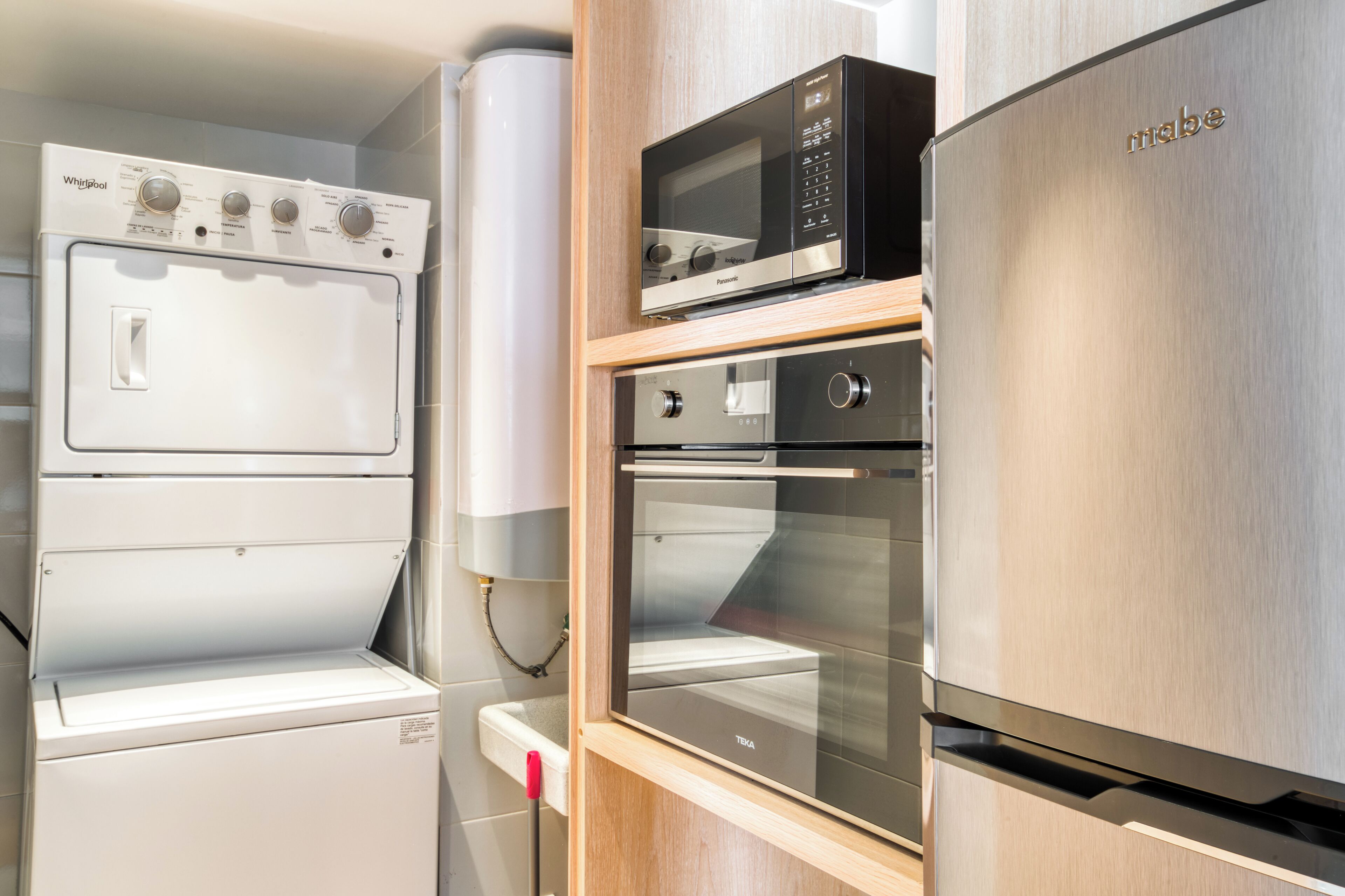 Eine kompakte Küche mit Edelstahlkühlschrank, Mikrowelle und eingebautem Backofen.