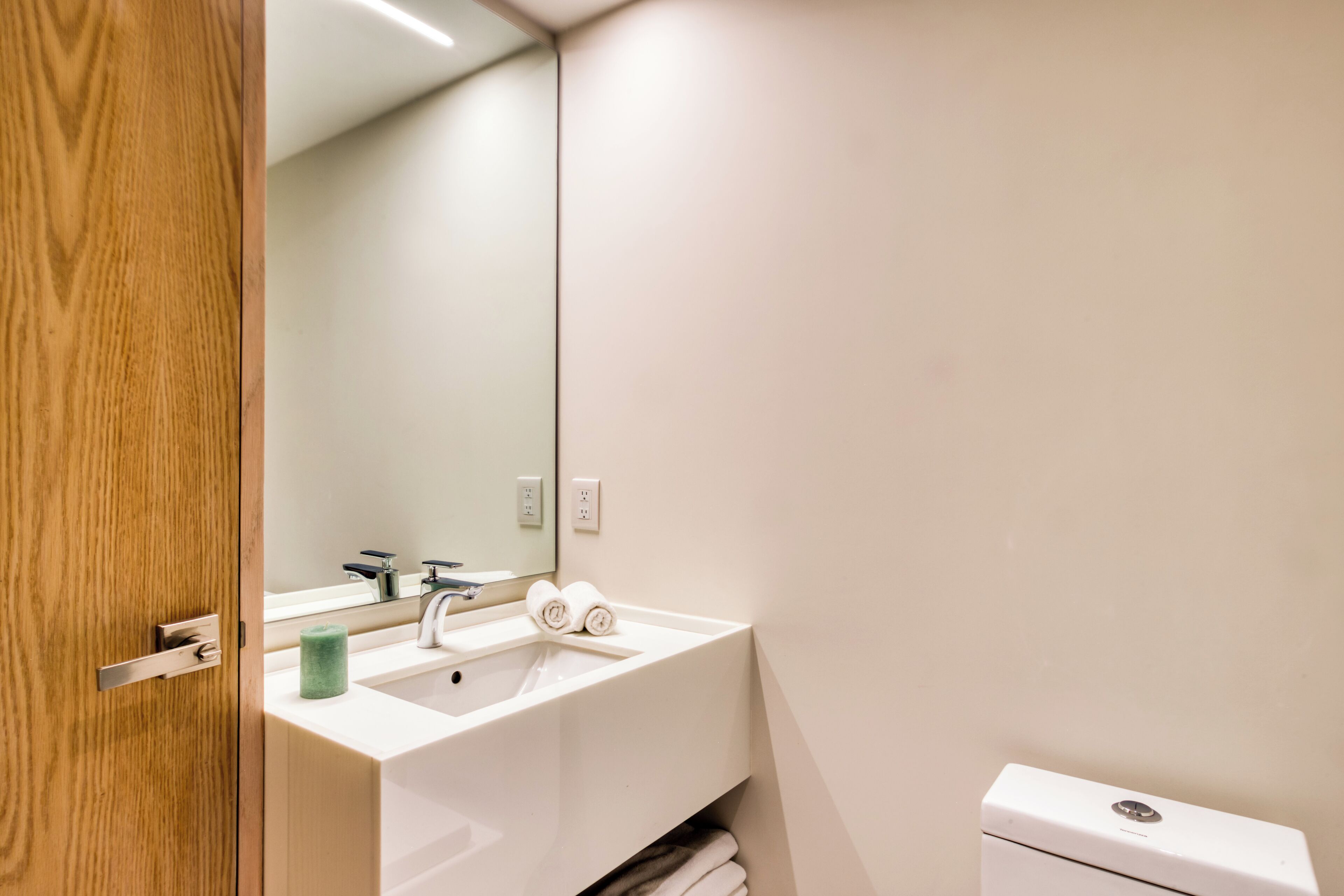A modern bathroom with a white sink, a mirror, and a toilet.