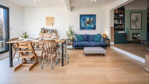 A spacious living area with a dining table, chairs, a sofa, and a large window.