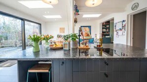 A modern kitchen with a large island, pendant lighting, and a view of the outdoors.
