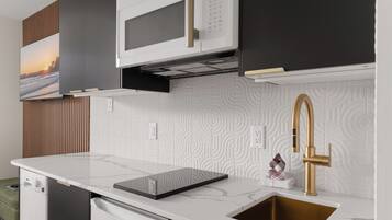 A modern kitchen with a built-in microwave, a stainless steel sink with a gold faucet, and a patterned backsplash.