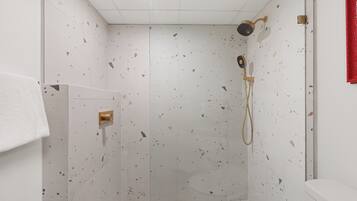 Una ducha con cabezal de ducha de mano y control montado en la pared.