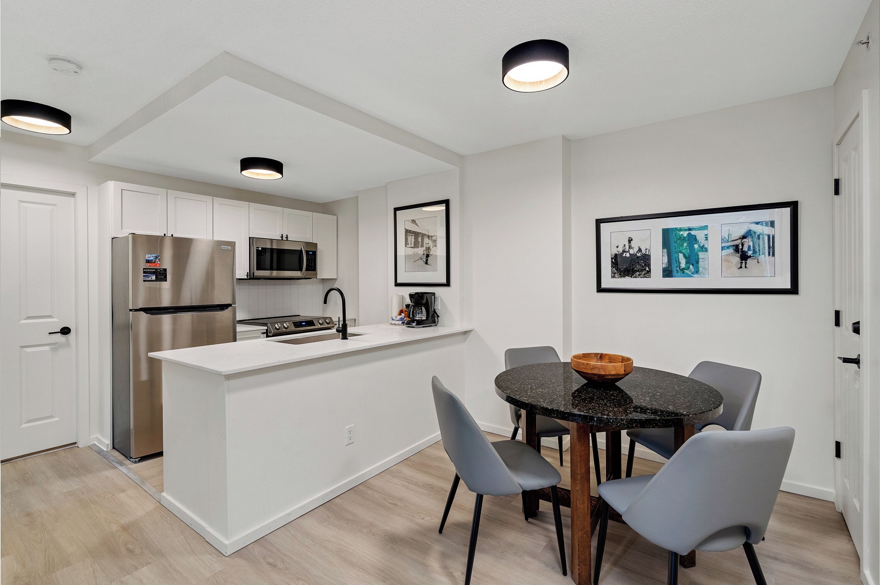 Una cocina moderna con armarios blancos, electrodomésticos de acero inoxidable y una isla central con asientos.