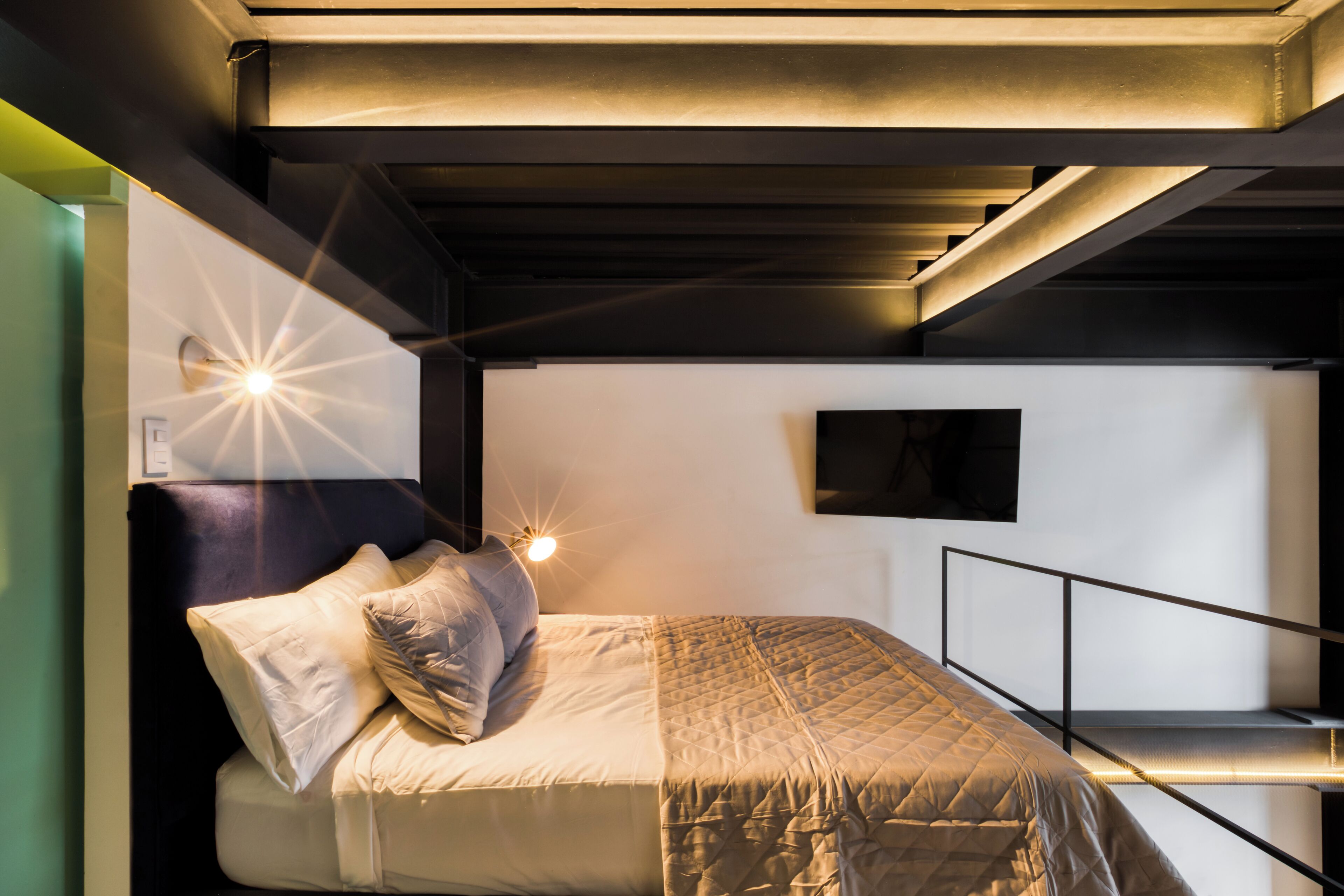 A bunk bed with a headboard, a bedside table, and a wall-mounted TV.