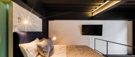 A bunk bed with a headboard, a bedside table, and a wall-mounted TV.