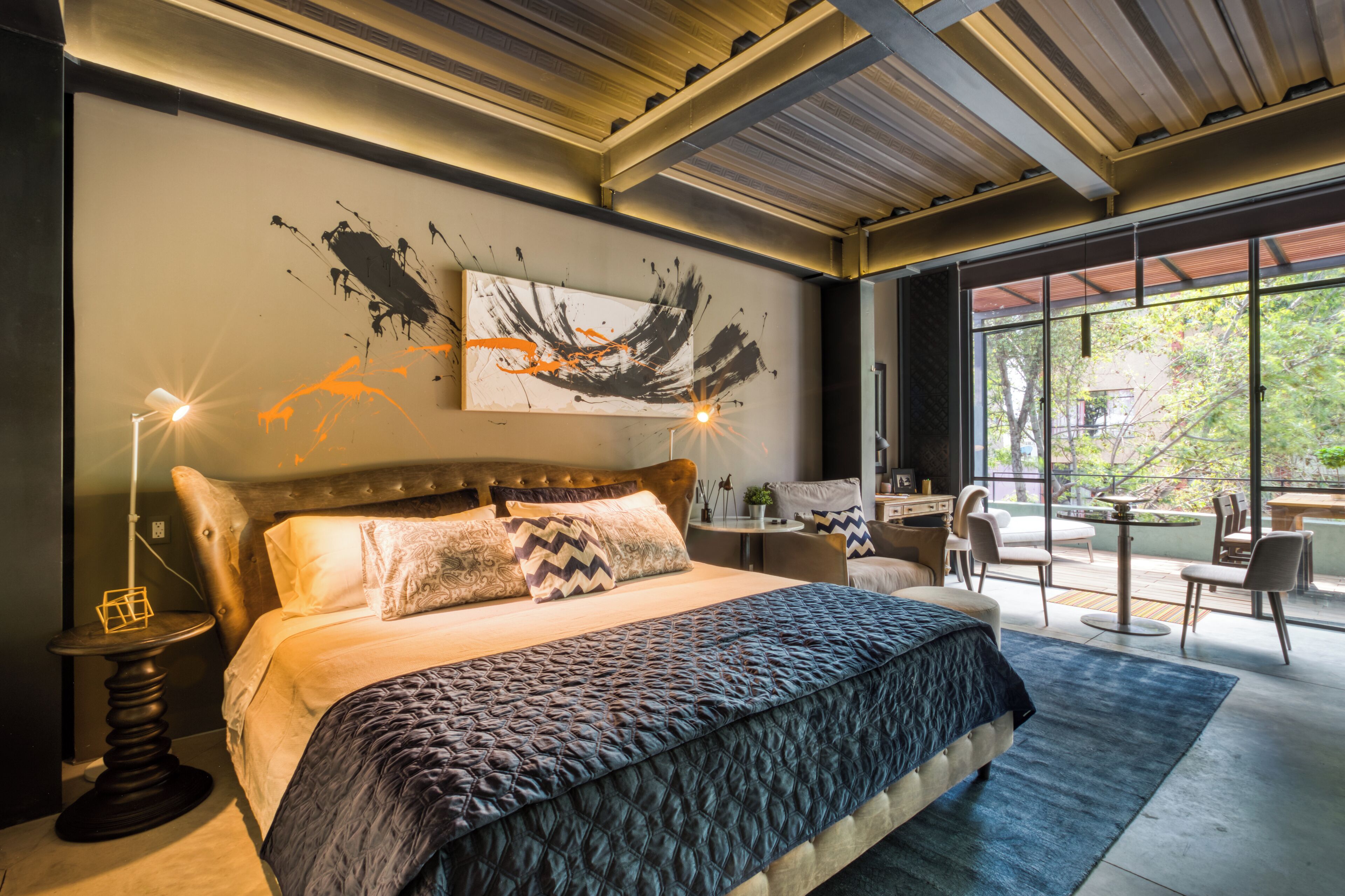 Ein modernes Schlafzimmer mit einem großen Bett, einem Schreibtisch und Blick ins Freie.