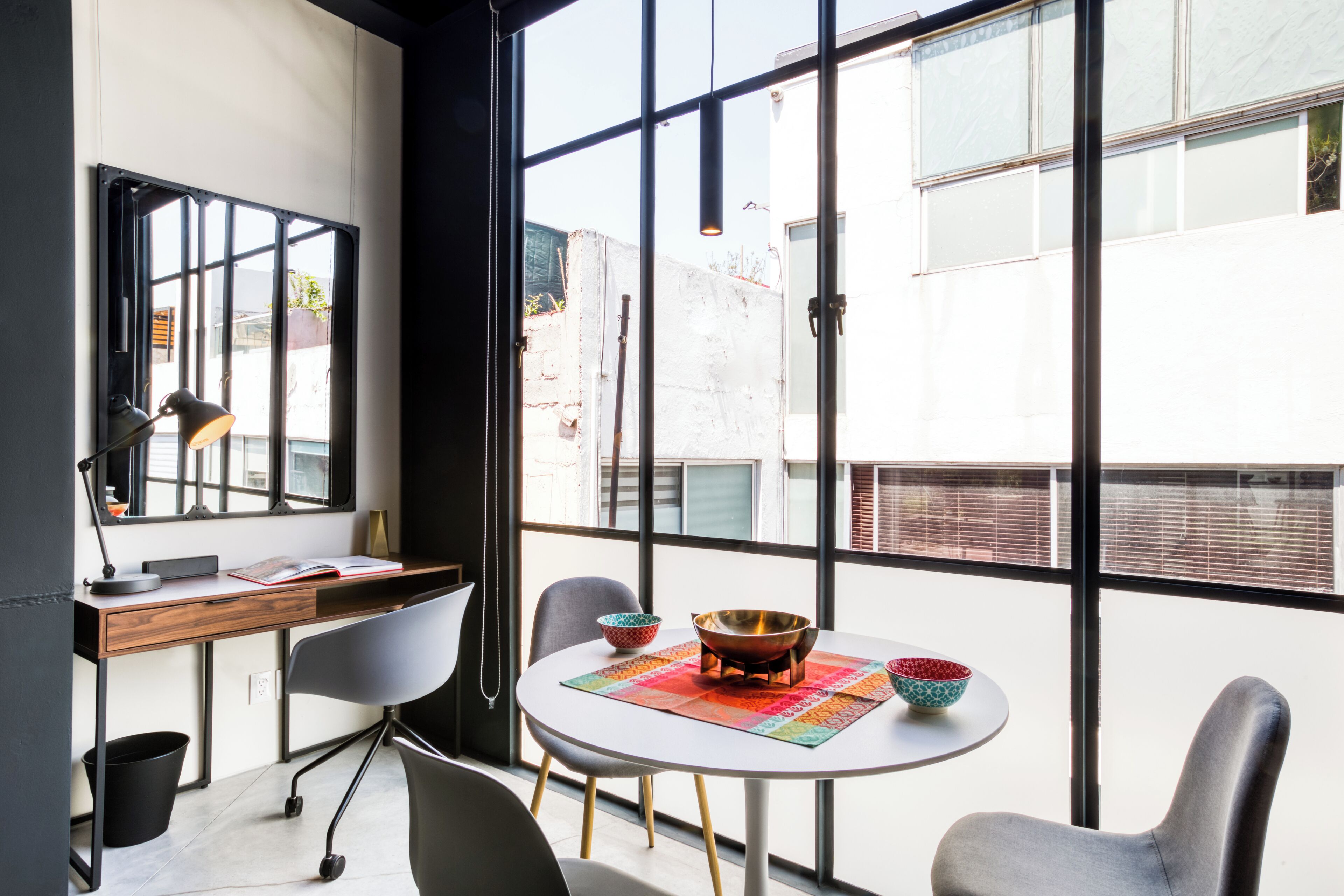 Un espace de travail moderne comprenant un bureau, des chaises et une table avec un bol et un livre.