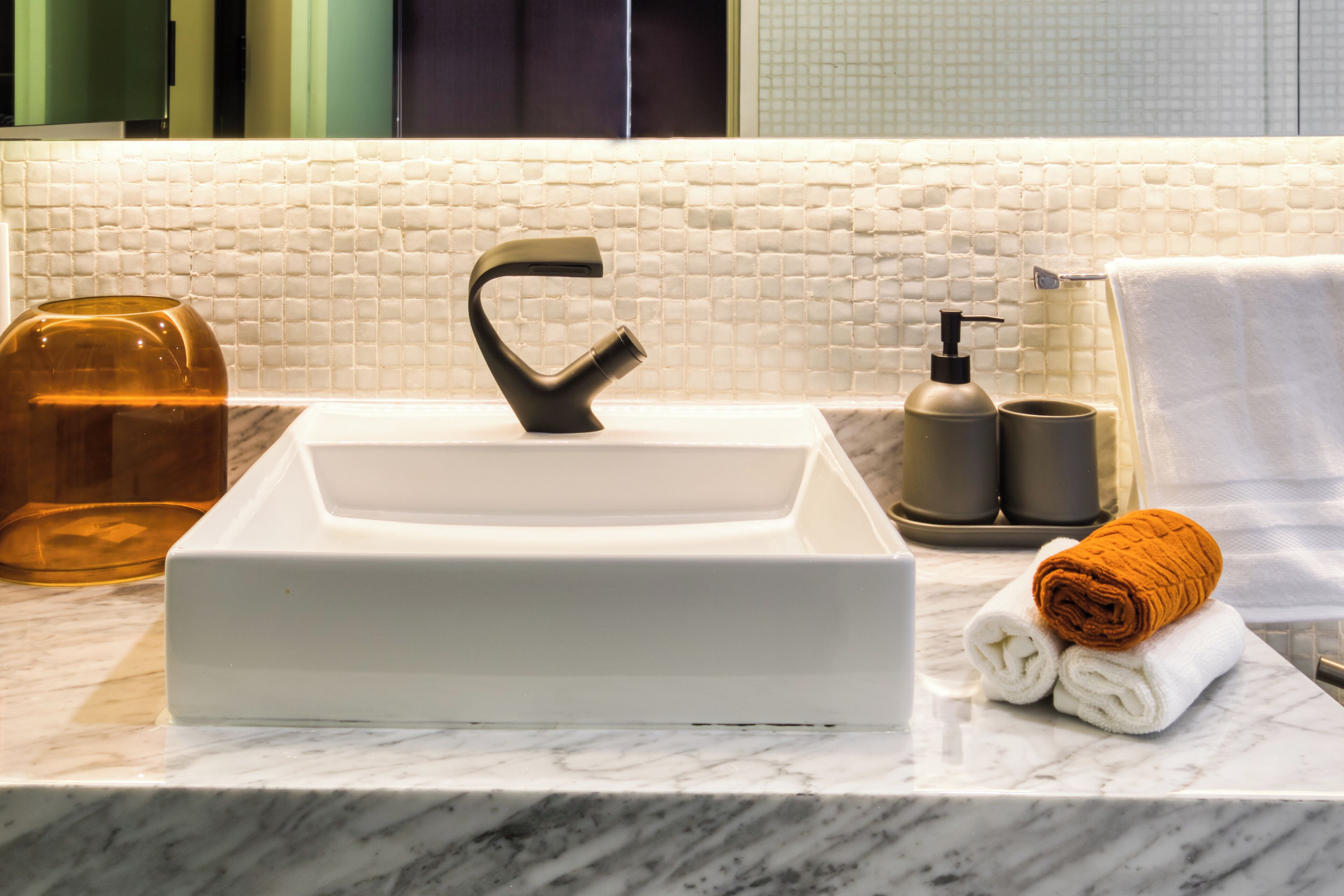 A bathroom sink with a modern faucet, a soap dispenser, and a towel on the counter.