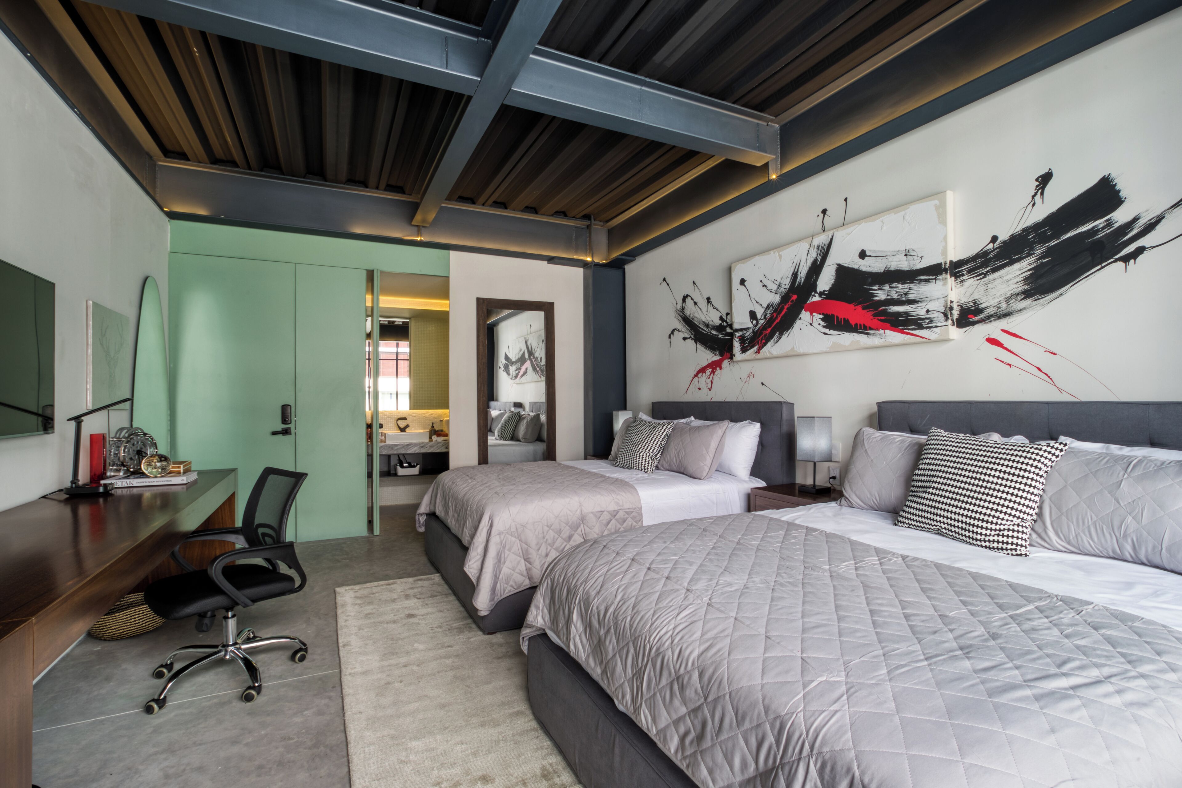 A modern bedroom with two beds, a desk, and a chair.