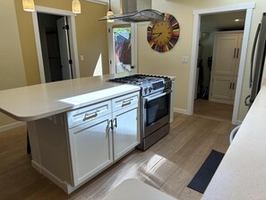 Cozinha moderna com ilha central, eletrodomésticos de aço inoxidável e um relógio de parede decorativo.