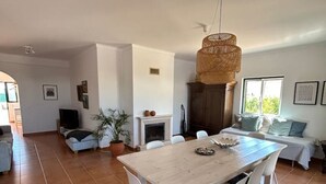 Un vaste espace de vie comprenant une table à manger, des chaises, une cheminée et une grande fenêtre.