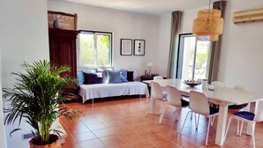 Une pièce spacieuse comprenant un coin repas, un lit à baldaquin blanc et une grande plante en pot.