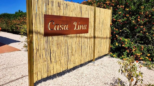 Une clôture en bois sur laquelle est accrochée une pancarte indiquant « Casa Lina ».