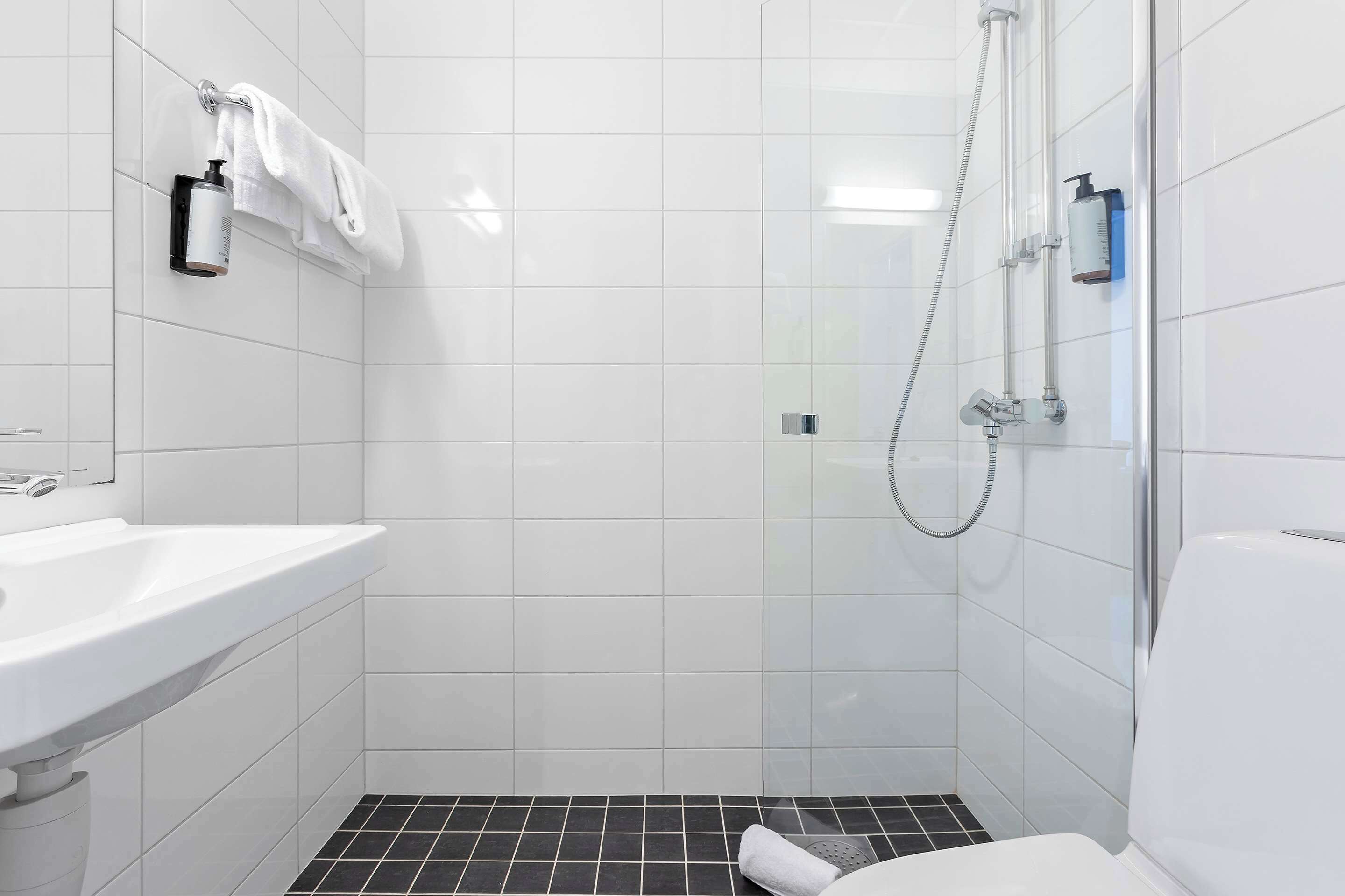 A modern bathroom with a white sink, a glass shower enclosure, and a toilet.