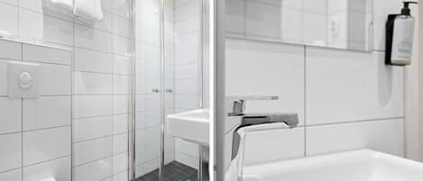 Un baño moderno con mampara de vidrio, un lavamanos blanco y una bañera grande.