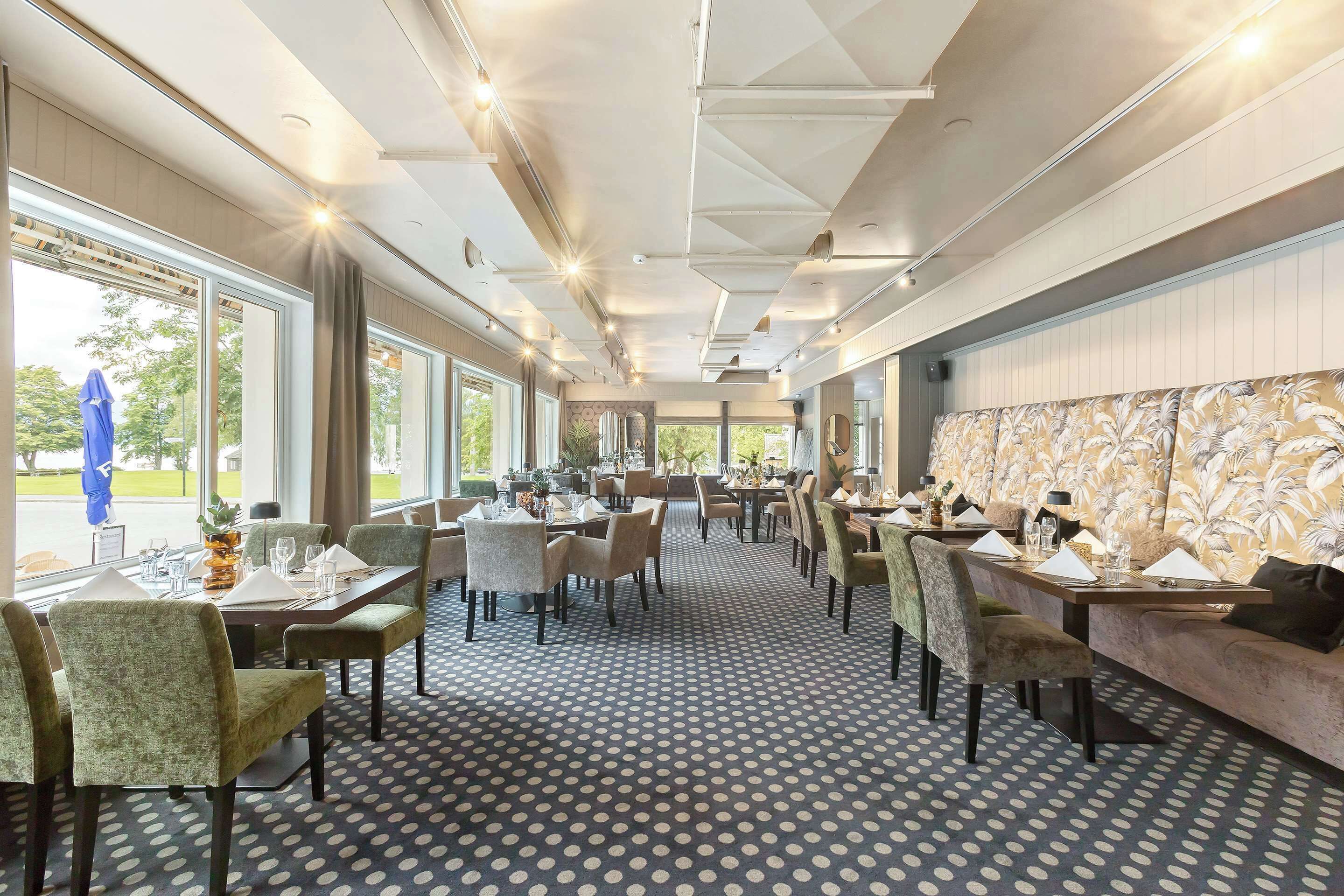 Een restaurant met een patroon vloer, tafels gedekt met witte tafelkleden, en stoelen.