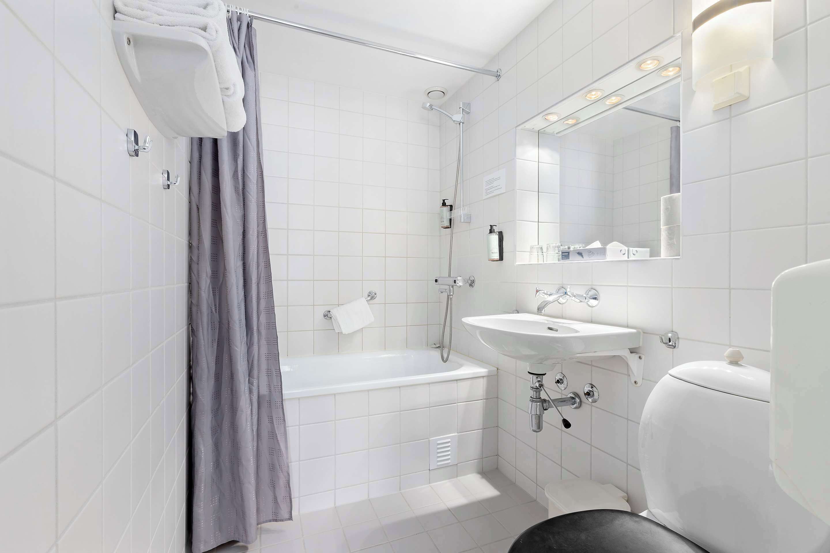 A modern bathroom with a bathtub, shower, and sink.