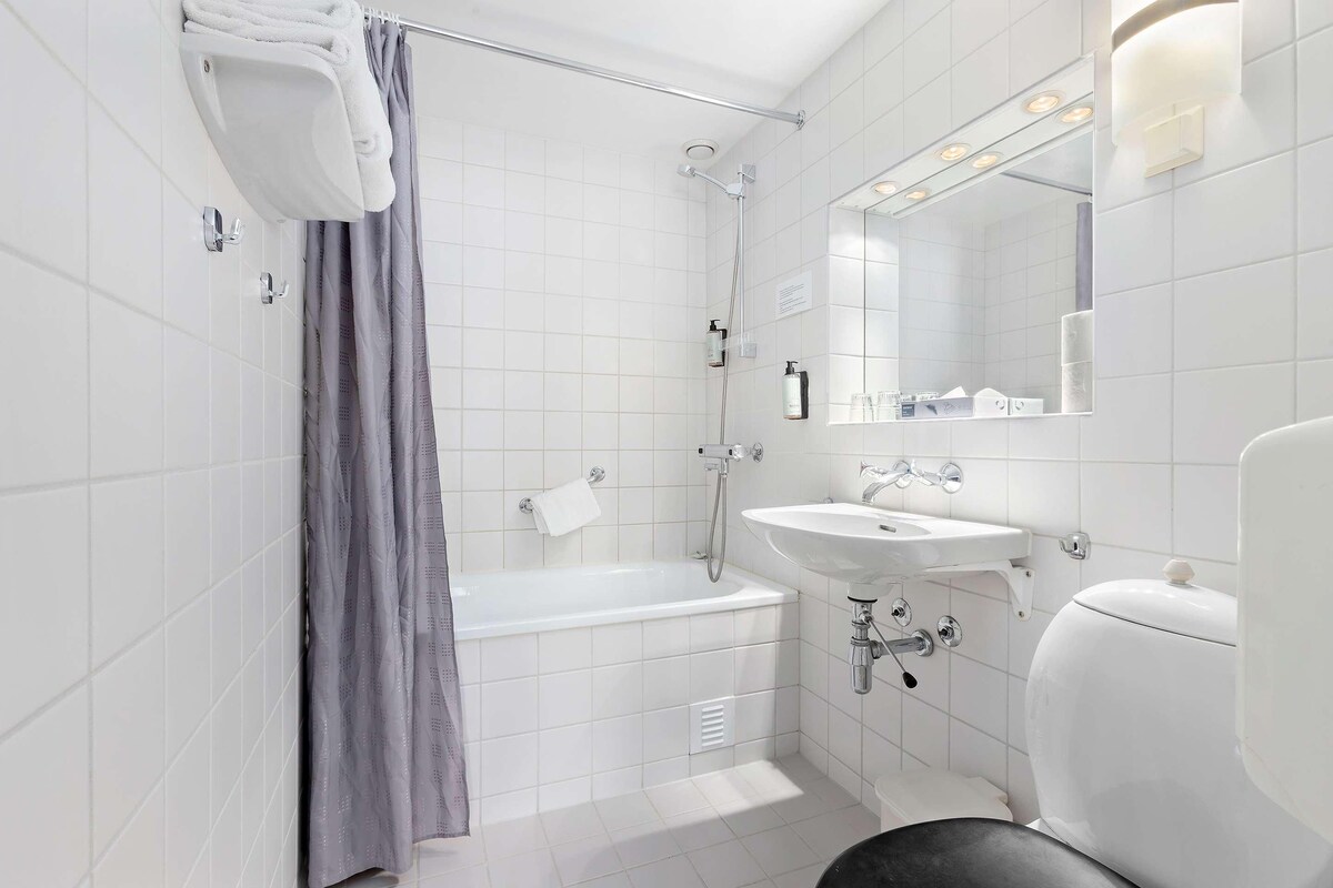 Een moderne badkamer met een bad, douche, wastafel en toilet.