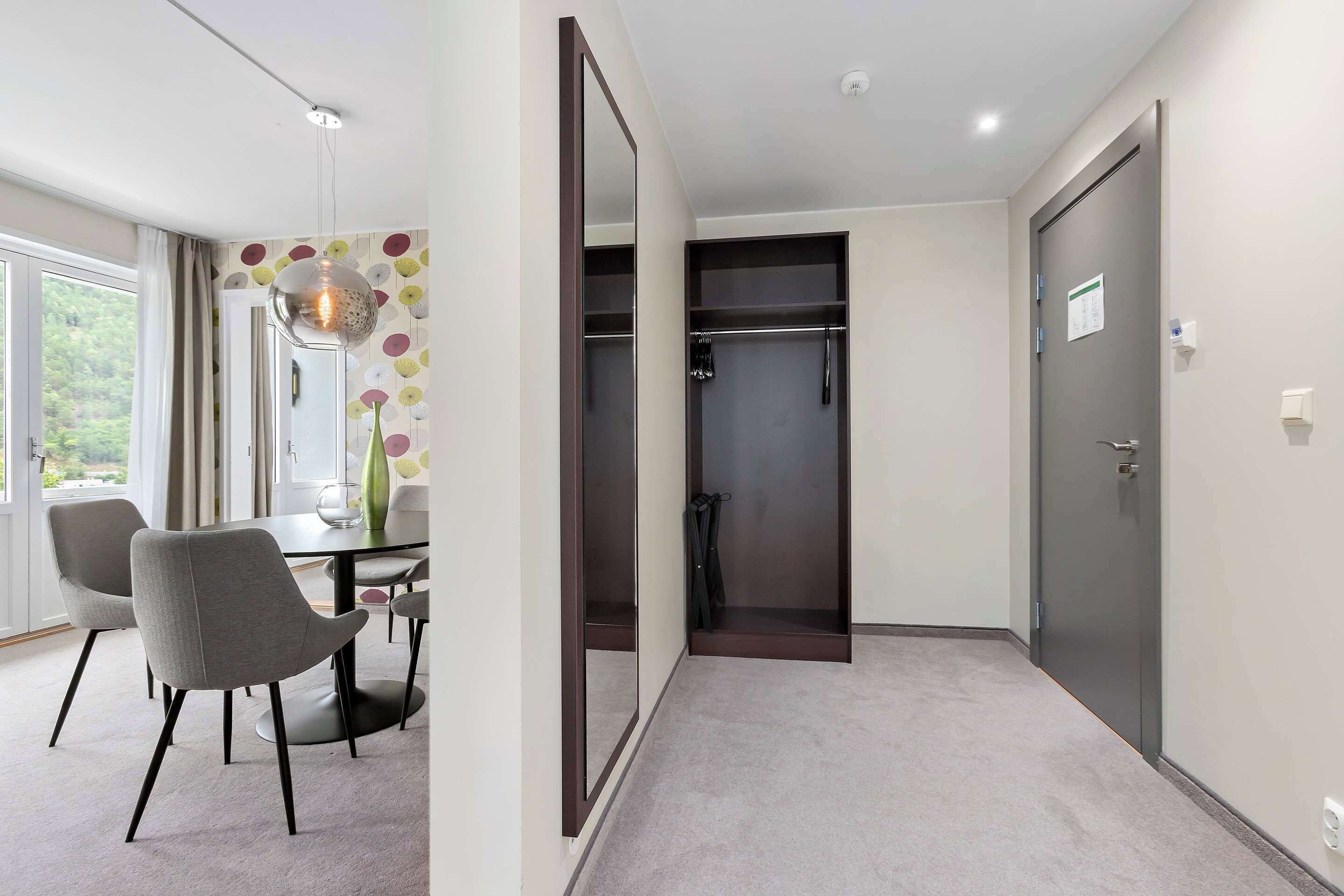 Quarto de hotel moderno com área de refeições, closet espaçoso e um espelho grande.