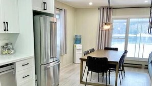 Una cucina moderna con mobili bianchi, un frigorifero in acciaio inossidabile e un'area pranzo con tavolo e sedie.