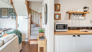 A modern kitchen with a microwave, a wooden shelf with glasses, and a potted plant on the counter. - The Hay Loft - UK45607 (Seaton, near Hornsea)