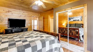 Een houten slaapkamer met een bed, een televisie en een schuifdeur naar een balkon.