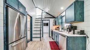 A modern kitchen with stainless steel appliances, teal cabinetry, and a wooden floor. - Broken Bow Cabin w/ Hot Tub, Fire Pit & Creek View (Broken Bow)