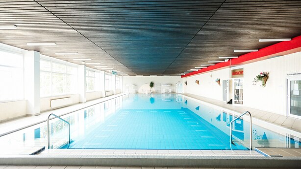 An indoor swimming pool with clear lanes, a tiled floor, and a ceiling with linear lighting fixtures. - Gemütliches Apartment_461, Schwimmbad & Sauna (Braunlage)