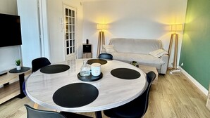 A modern, well-lit room with a round dining table, black chairs, a sofa, and a bed. - L'escapade Vue Mer - Hardelot (Neufchâtel-Hardelot)