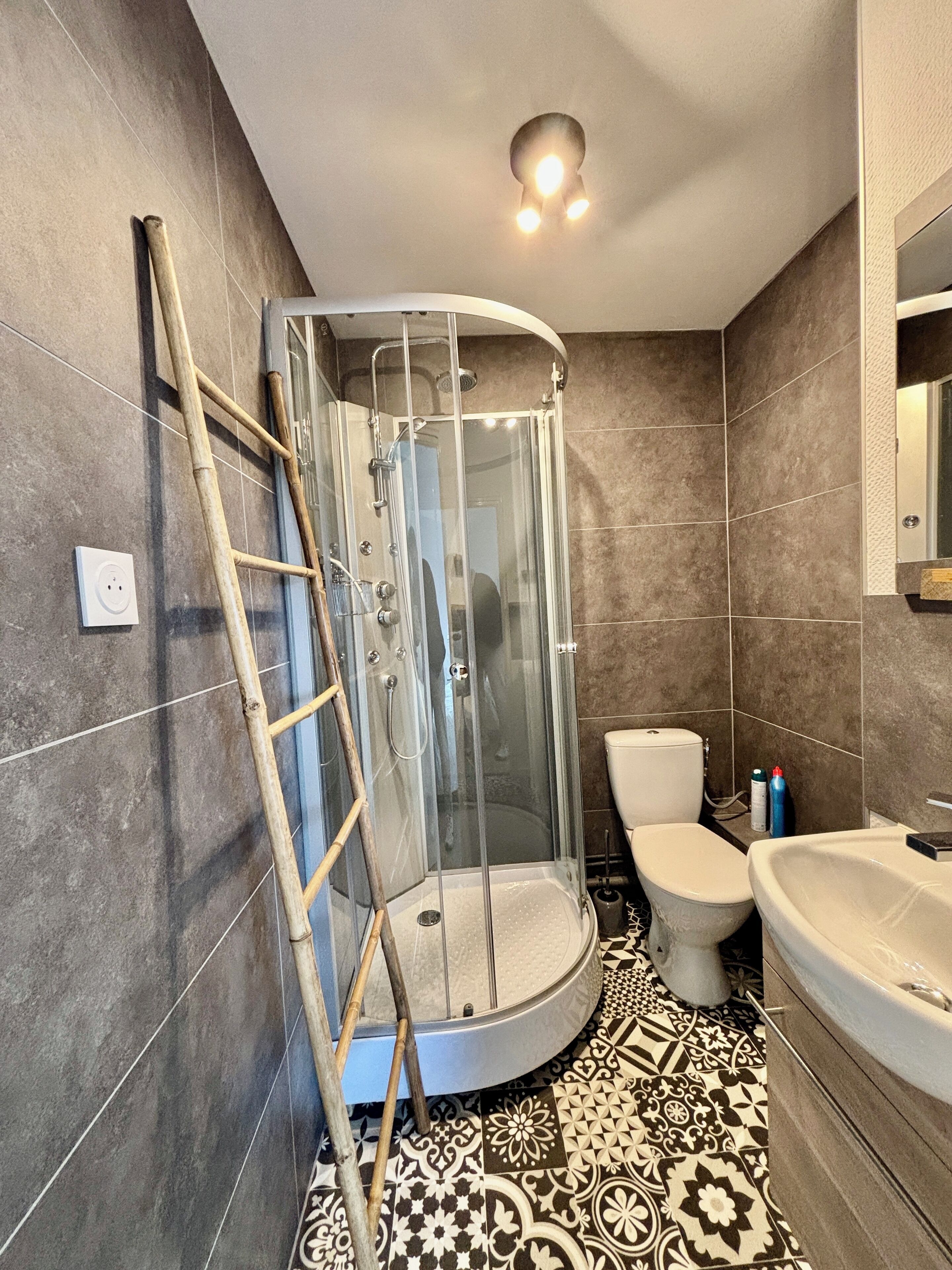 A bathroom with a glass-enclosed shower, a toilet, and a sink.